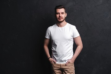 young fashion man posing for the camera on black background