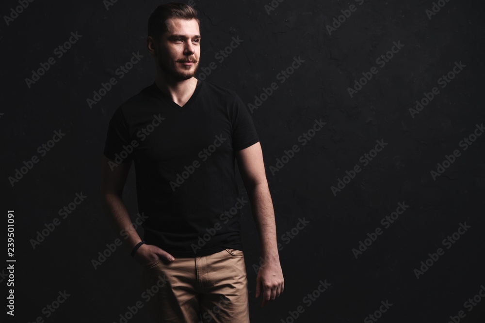 Wall mural young fashion man posing for the camera on black background