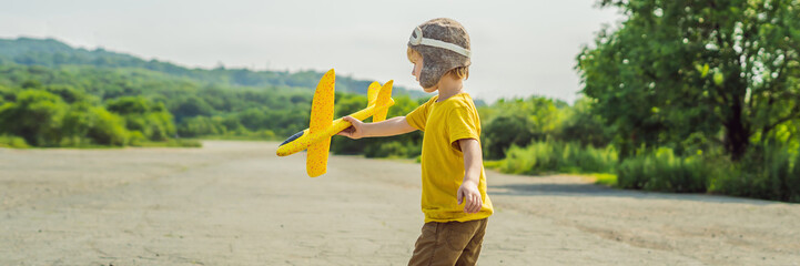 Happy kid playing with toy airplane against old runway background. Traveling with kids concept BANNER, LONG FORMAT
