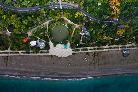 Vertical aerial photo of a beach, a beautiful park road. Photo from top to bottom, blue water,