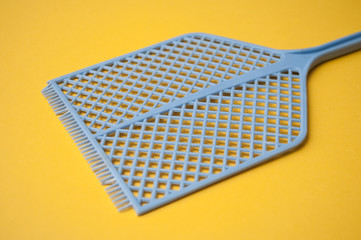 closeup of blue fly swatter on yellow  background