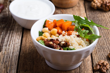 Healthy salad bowl with baked pumpkin,  chickpeas, quinoa, arugula, walnuts