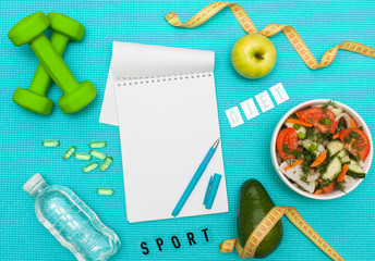 Flat lay. Top view with copy space. Healthy lifestyle, food, sport or athlete's equipment. Top view of the sports equipment, dumbbells, fitness mat, water and fresh salad, fruits and vitamins