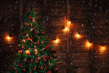 a Christmas tree decorated with toys ornaments beads red garland on wooden brown wall copyspace