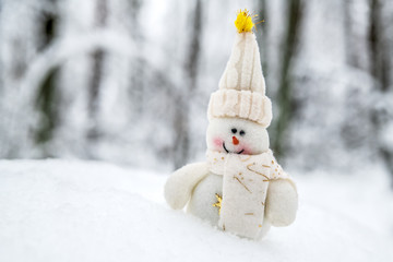 Smiling snowman in a hat and scarf in a snowdrift.