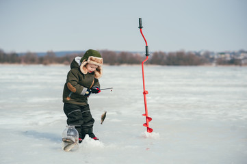 boy fishing on winter. Cute boy catches fish in the winter lake. Winter. Outdoor