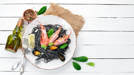Black spaghetti. Black pastas with seafood and lemon. Shrimp and mussels. On the old background. Top view. Free space for your text.