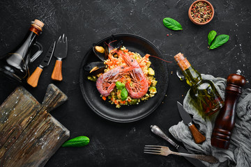 Bulgur with shrimp, mussels and vegetables. On the old background. Top view. Free space for your text.