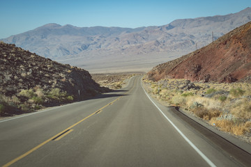 View from the endless road through Death Valley National Park (California State Route 190), with a view of the Sierra Nevada mountains in the background on a hazy sunny day