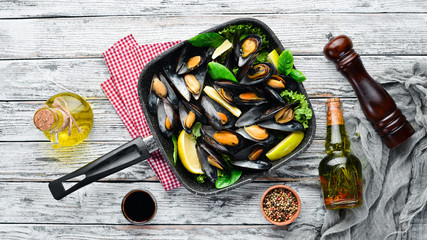 Fried mussels in a frying pan. Top view. Free space for your text. On the old background.