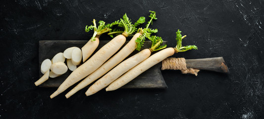 Radish Daikon on a black background. Radish. Vegetables. Top view. Free space for your text.