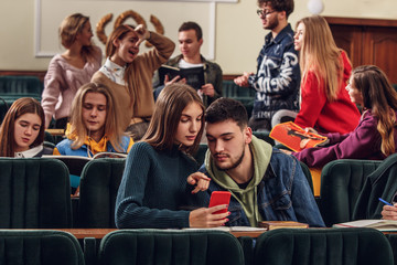 The group of cheerful students sitting in a lecture hall before lesson. The education, university, lecture, people, institute, college, studying, friendship and communication concept