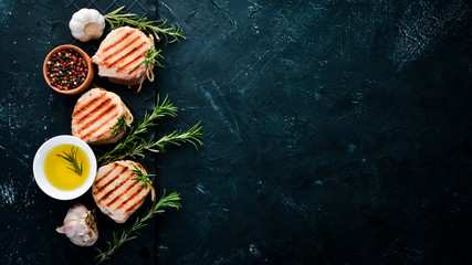 Baked meat medallions with rosemary. Grill, barbecue. On a black stone background. Top view. Free copy space.