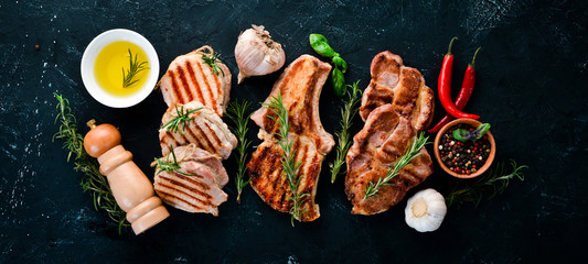 Grilled Meat. Seth meat. Grill, barbecue. On a black stone background. Top view. Free copy space.