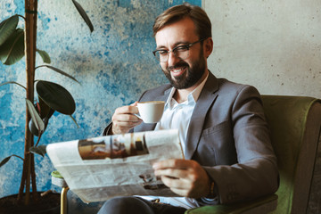 Smiling businessman wearing suit reading newspaper