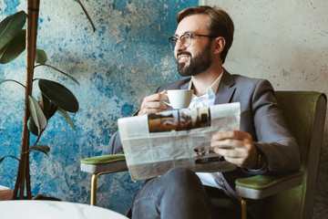 Smiling businessman wearing suit reading newspaper