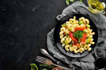 Pasta with vegetables. On a black background. Top view. Free space for your text.