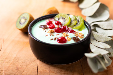 Healthy food colorful Yogurt Breakfast Bowl  with kiwi, flax seeds, Granola, and red currants in black ceramic bowl with copy space