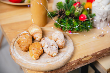 Freshly baked croissants on a wooden round table against a wooden table