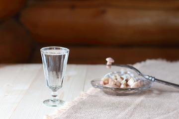 A glass of vodka and a snack from mushrooms.