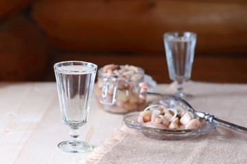 A glass of vodka and a snack from mushrooms.