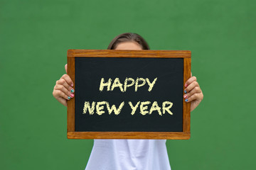 girl holding a blackboard with the message happy new year written
