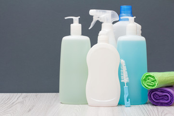 Bottles of detergent and garbage bags on gray background.