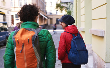 group of tourists walking on the streets of Lviv. back view of Happy smiling woman with friends tourists in warm outdoor wear walking outdoors at autumn or spring day