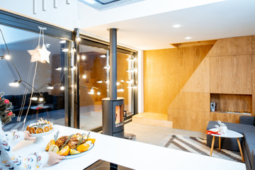 Beautiful modern interior with fireplace and festive meals on the table during winter holidays