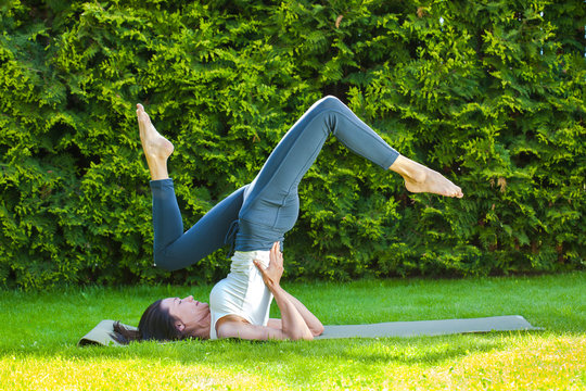 woman doing yoga on a green grass at summer day