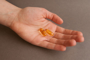 Fish oil in capsules, in hand, close-up. The concept of vitamins for women.