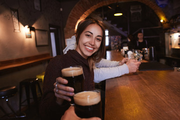 smiling cheerful woman sitting in the pub with beer