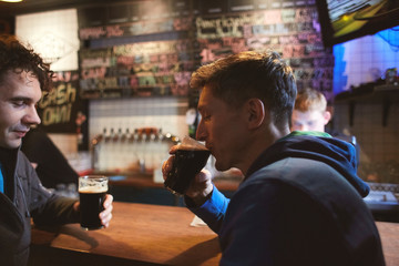 two guys friends sitting in the pub with glasses of beer