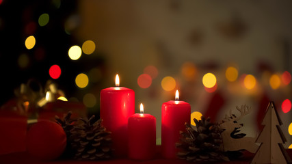 Big festive candles burning near Christmas decorations, lights on background