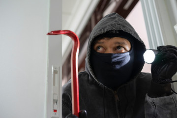 Thief With Flashlight And Crowbar Entering Into House