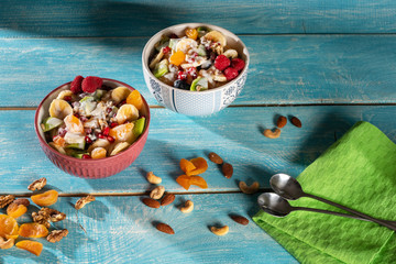 Porridge with berries and nuts in a bowl with a spoon for healthy breakfast on rustic wooden background. top view