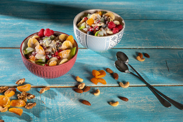 Porridge with berries and nuts in a bowl with a spoon for healthy breakfast on rustic wooden background. top view