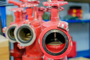 Three red fire hydrants with valves are in the warehouse