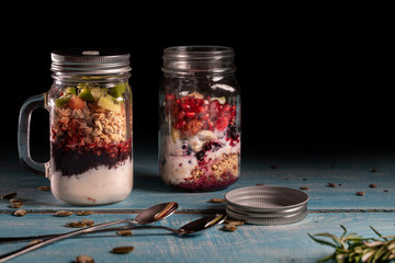 Muesli, fresh berries and yogurt in glass mason jar on wooden table. Healthy breakfast