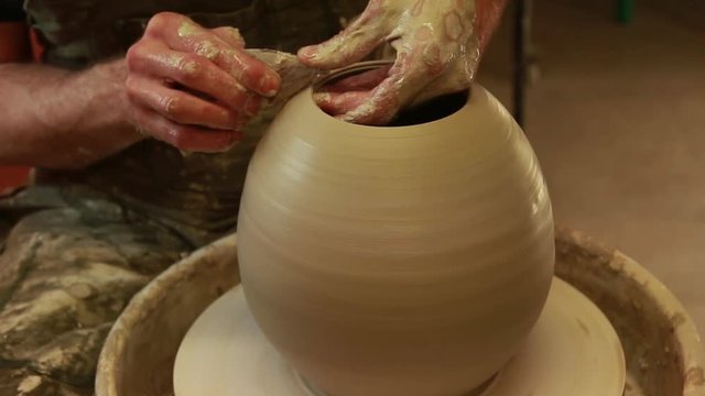 Artist potter in the workshop creating a ceramic vase. Hands closeup. Twisted potter's wheel. Small artistic craftsmen business concept.