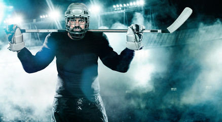 Ice Hockey player in the helmet and gloves on stadium with stick.