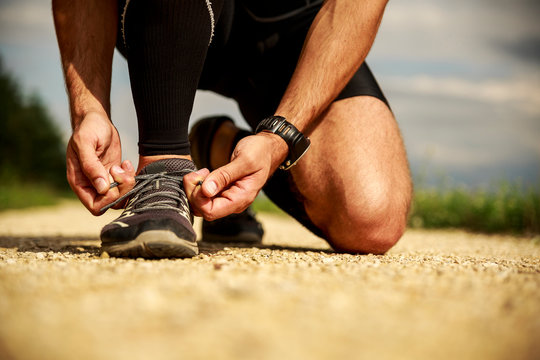 Wysportowany mężczyzna wiąże buty. Biegacz. Sport. Zdrowy styl życia