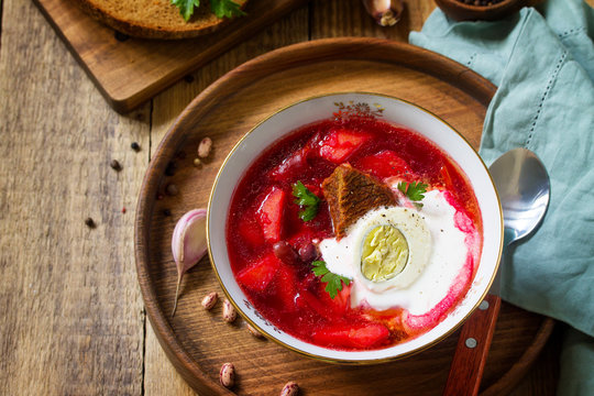 Traditional Ukrainian Russian borscht. Borsch, beetroot Soup with Sour Cream in bowl on kitchen wooden table. Copy space.