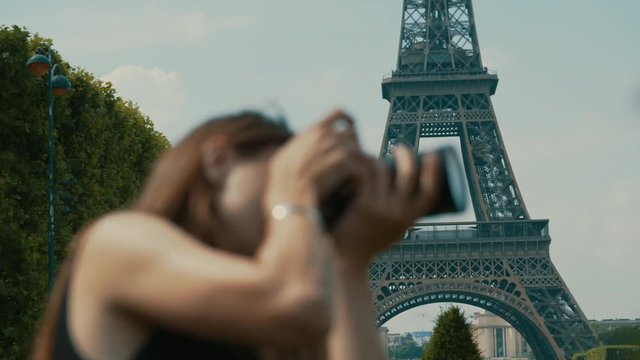 Profile view of a woman taking a photograph with a digital camera in the Eiffel Tower city Park