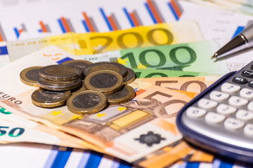 Business diagram on financial report with coins, bills, pen and calculator