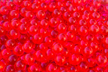Water red gel balls with bokeh. Polymer gel. Silica gel. Balls of red hydrogel. Crystal liquid ball with reflection. Red balls texture background