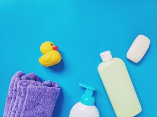 Flat lay baby natural baby bath products for skin and hair care. Shampoo, purple towel, liquid soap and rubber duck toy
