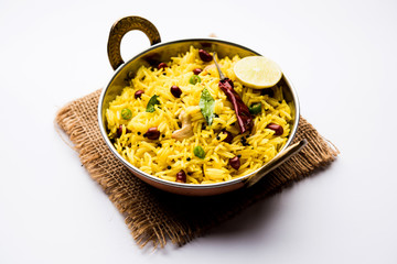 Lemon Rice is a South Indian turmeric rice or maharashtrian recipe called fodnicha bhat using leftover rice garnished with nuts curry leaves and lemon juice, selective focus