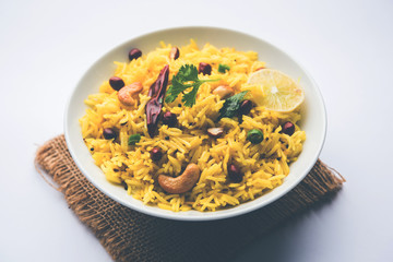 Lemon Rice is a South Indian turmeric rice or maharashtrian recipe called fodnicha bhat using leftover rice garnished with nuts curry leaves and lemon juice, selective focus