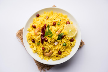 Lemon Rice is a South Indian turmeric rice or maharashtrian recipe called fodnicha bhat using leftover rice garnished with nuts curry leaves and lemon juice, selective focus